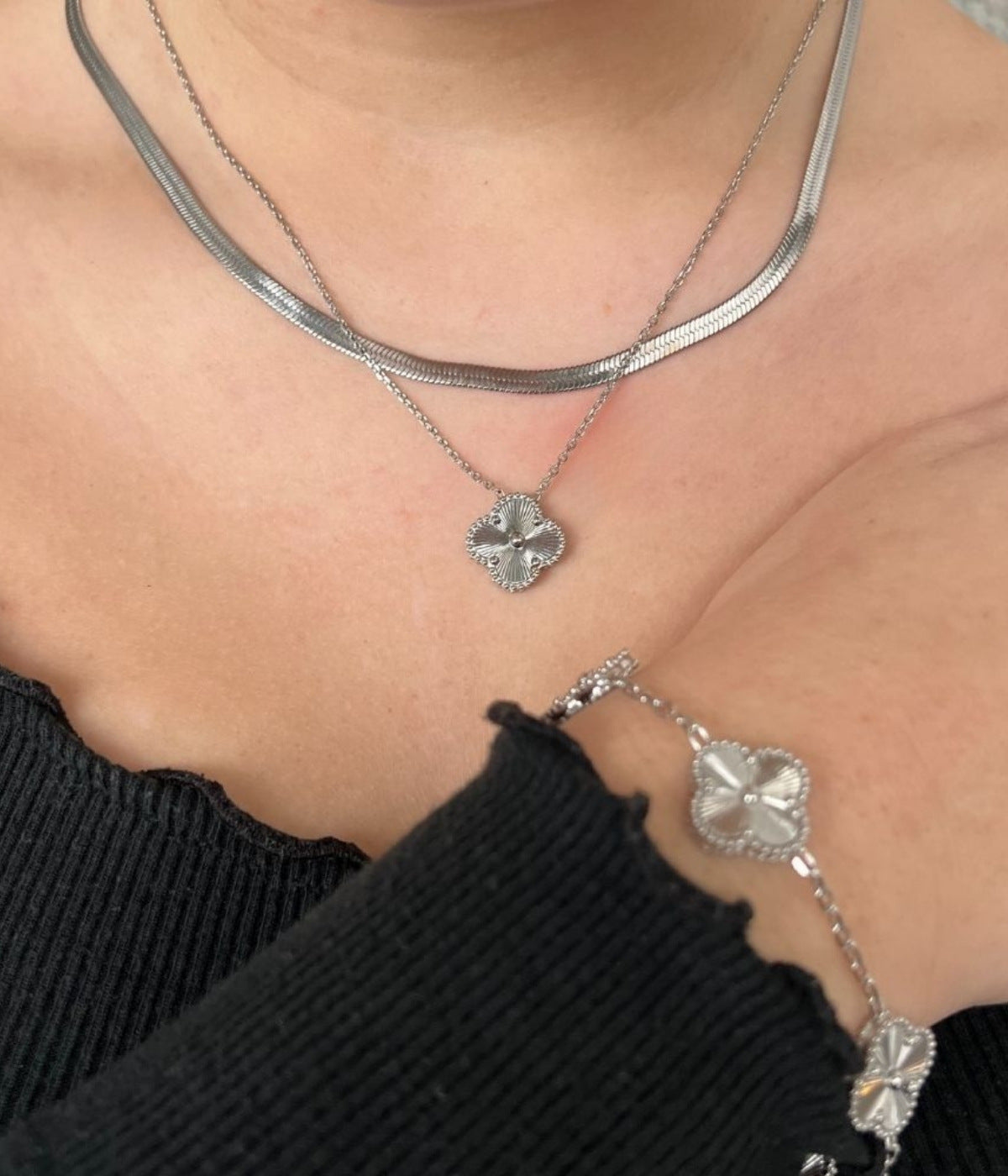 Silberne Kette mit vierblättrigen Kleeblatt Anhänger und silbernes Armband mit Kleeblatt Anhänger getragen von einer Frau