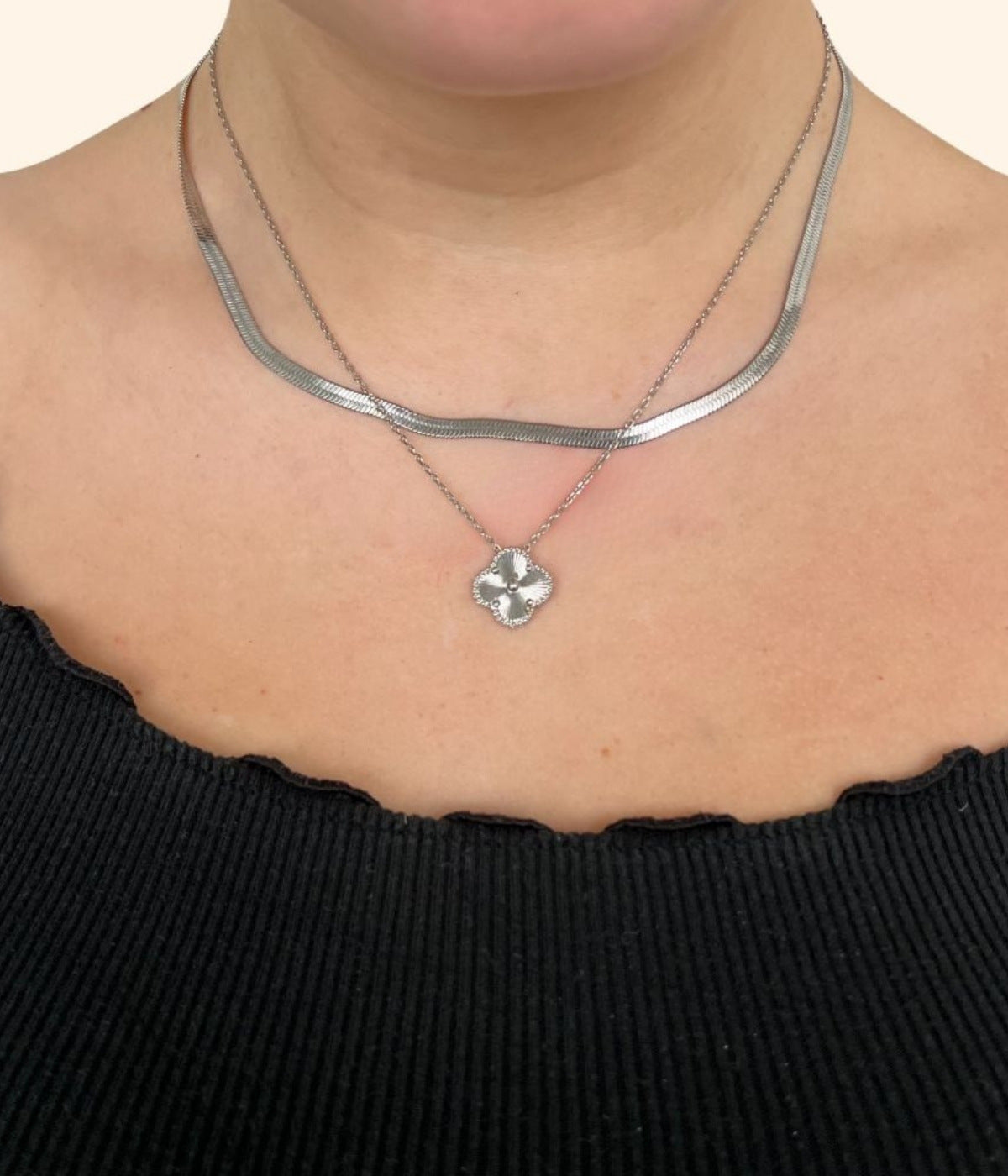 Eine frau trägt zwei goldene Ketten. Einmal eine Choker Kette und einmal eine Kette mit goldenem vierblättrigen Kleeblatt Anhänger