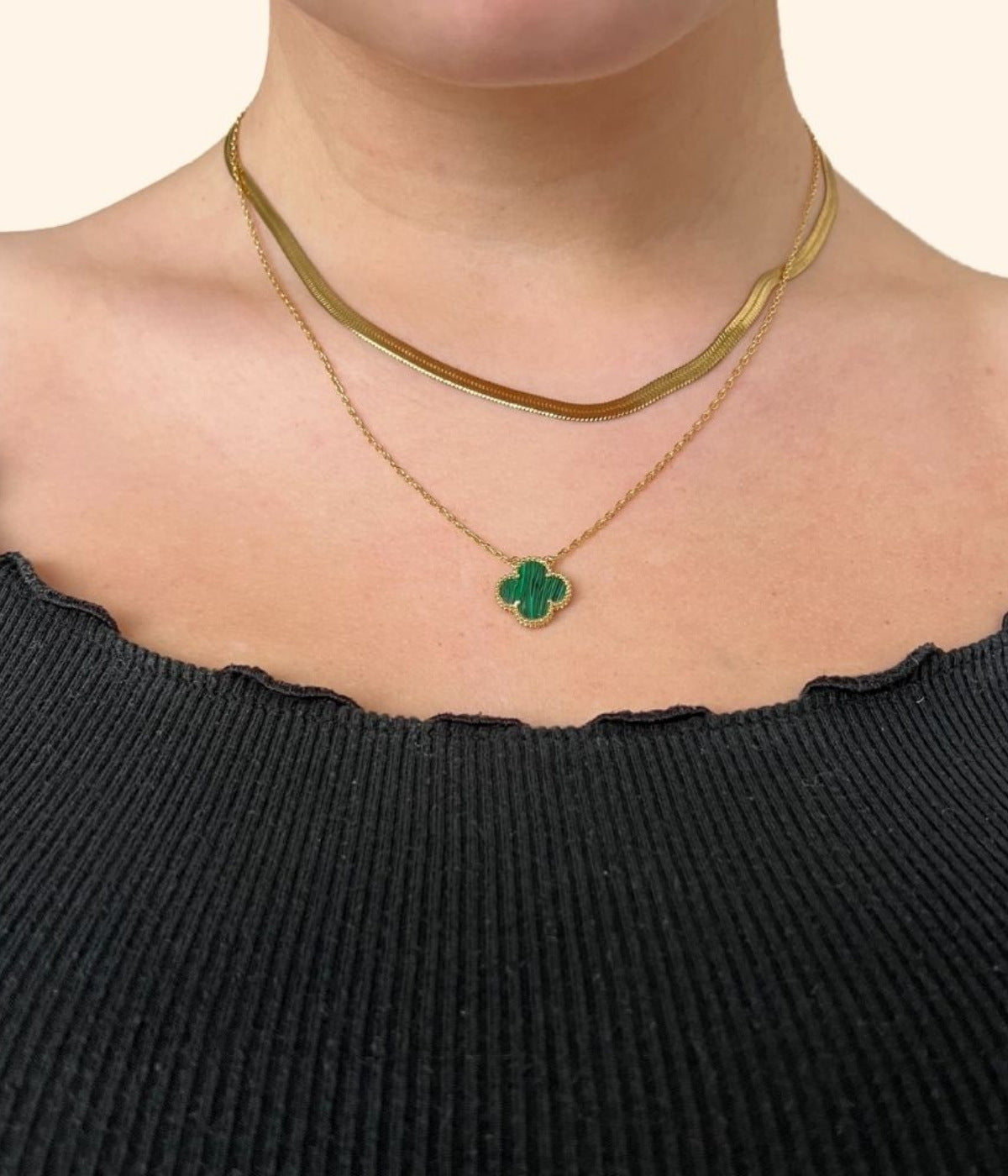 Goldene Kette mit grünen vierblättrigen Kleeblatt Anhänger mit einer goldenen Choker Kette kombiniert getragen von einer Frau