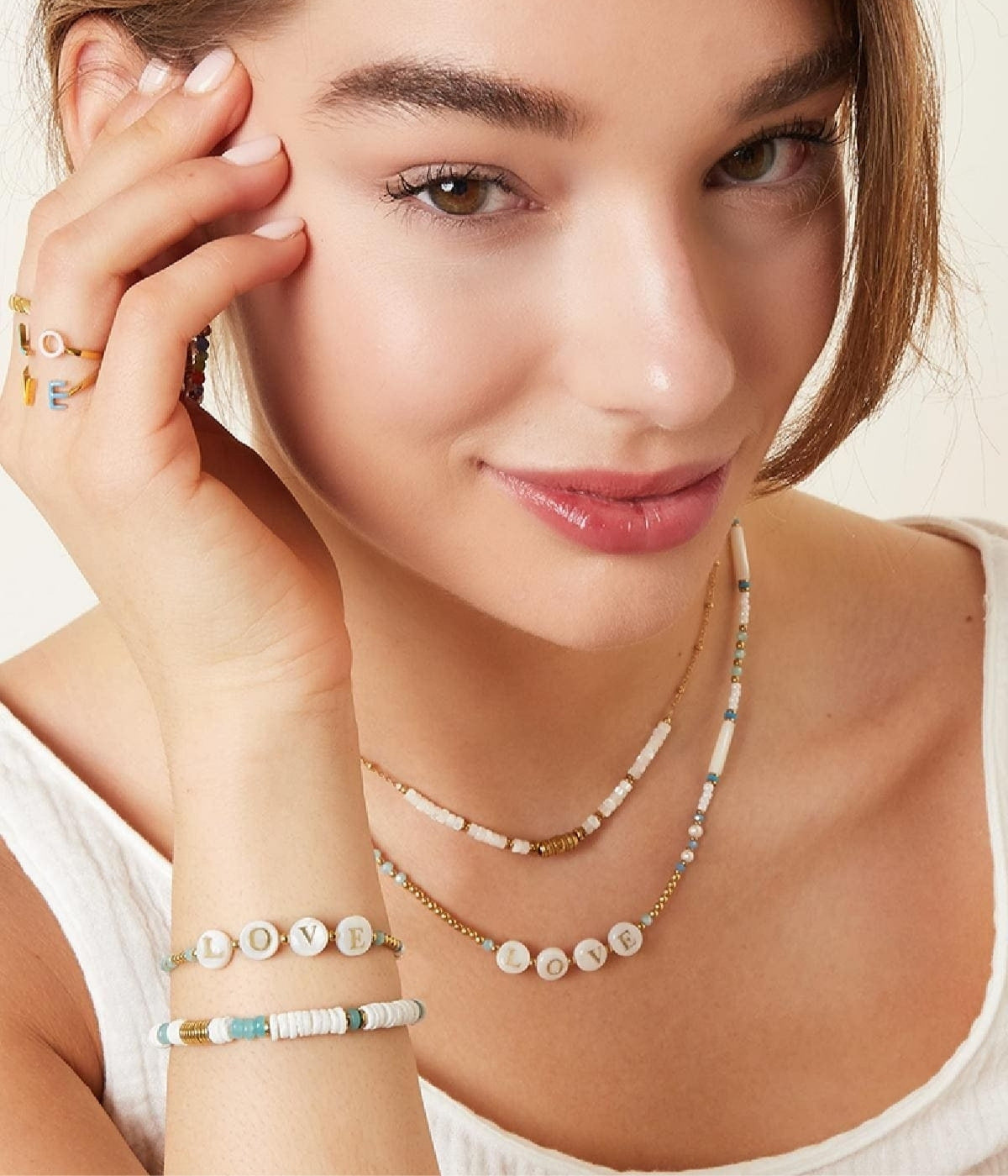 Kette und Armband in blauen und goldenen Akzenten mit den Buchstaben LOVE getragen von einer Frau