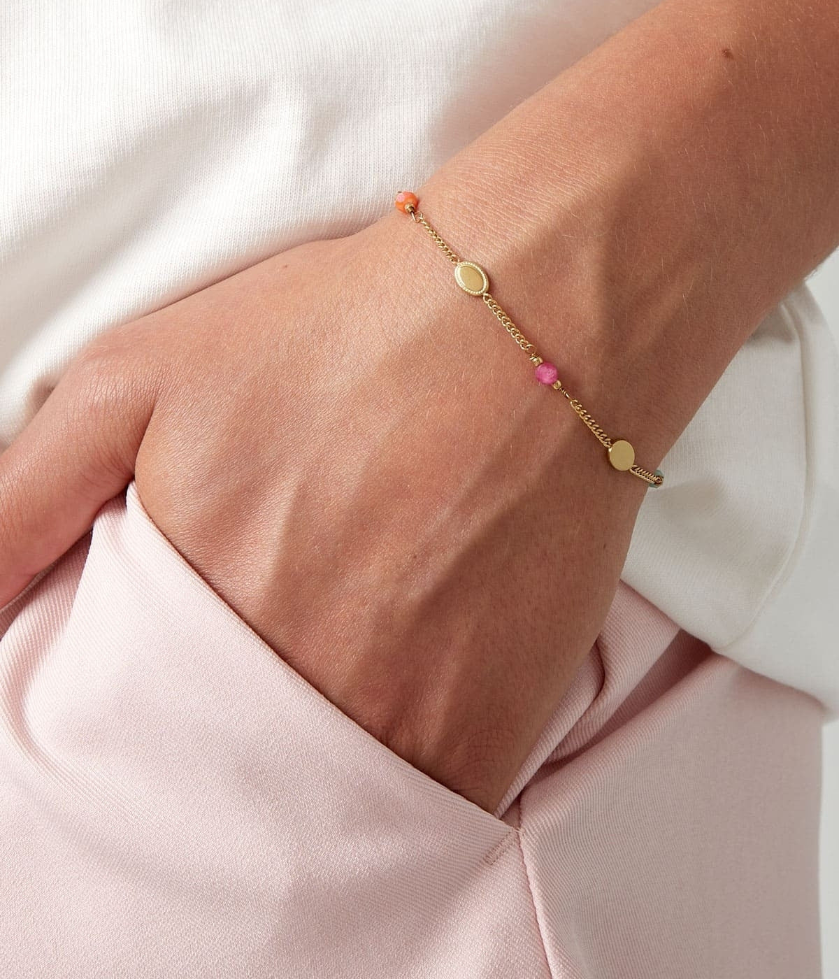 goldenes Plattenarmband mit Bunten Steinen angezogen an einer Frauenhand präsentiert