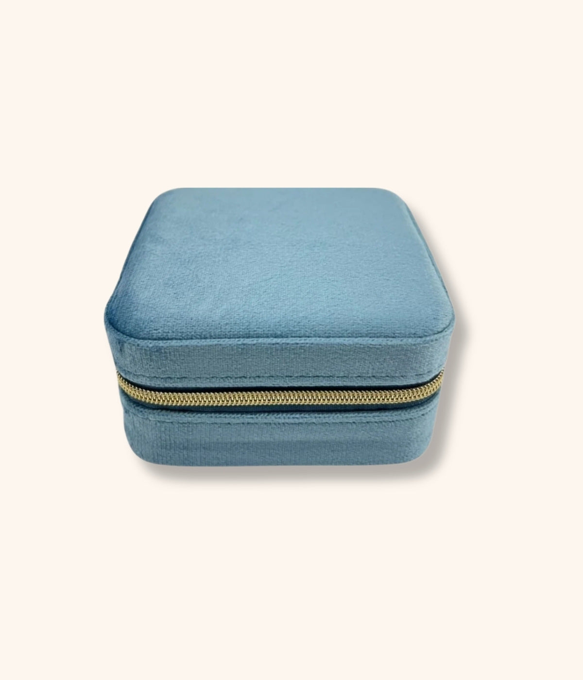 Kleine quadratische Tasche zur Schmuckaufbewahrung. Tasche ist in blauen Velourstoff und goldenem Reisverschluss. Die Schmucktasche liegt auf weißem Hintergrund