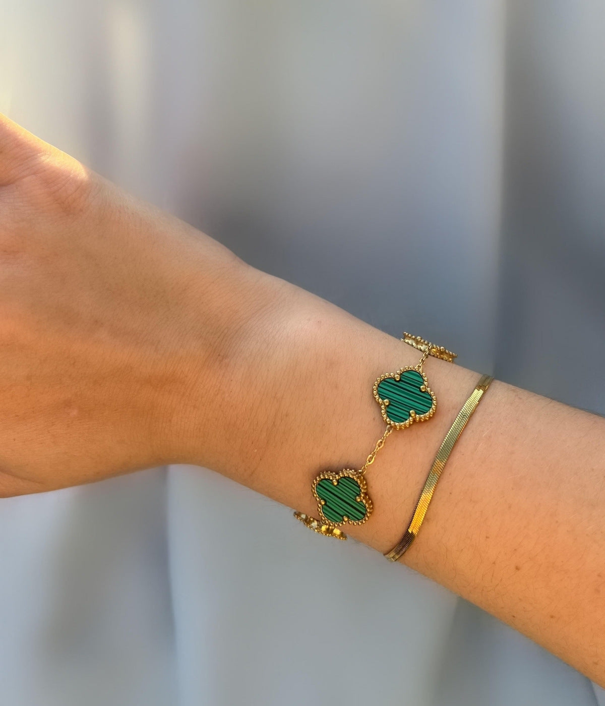 Grünes Kleeblatt Armband aus Gold am Handgelenk getragen – eleganter Schmuck als Glücksbringer