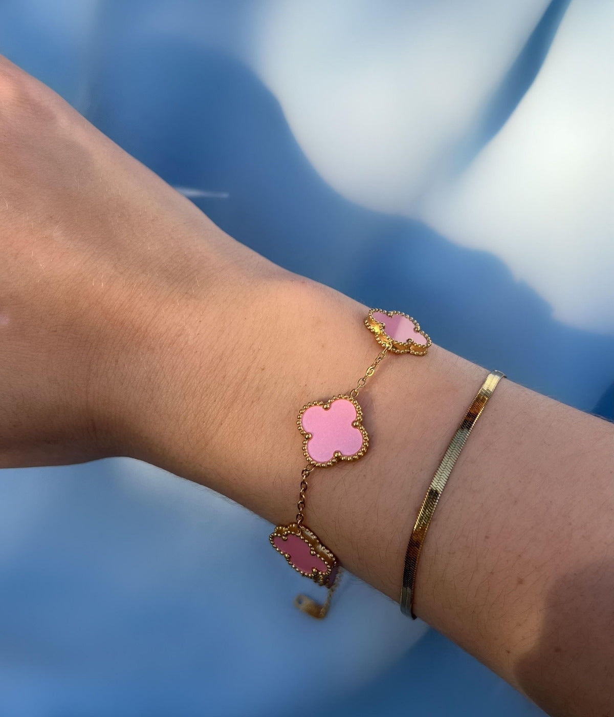 Zartes rosa Kleeblatt Armband aus Gold am Handgelenk getragen – femininer Schmuck mit Symbolcharakter