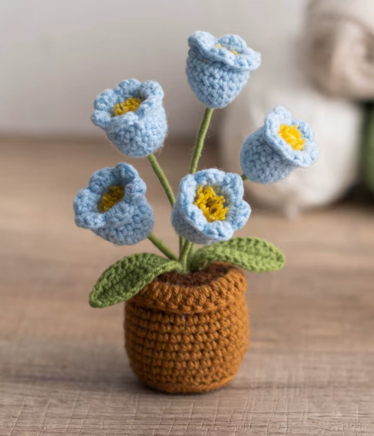 Hellblaue gehäkelte Glöckchenblumen im Topf – stilvolle Blume aus Wolle