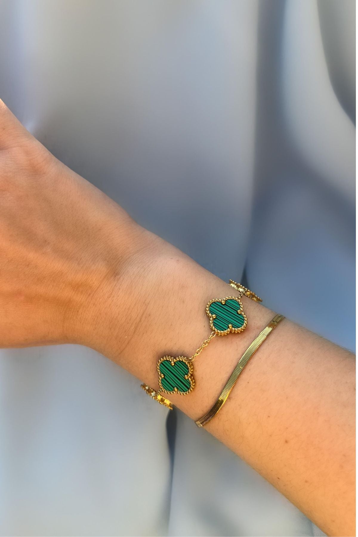 Grünes Kleeblatt Armband aus Gold am Handgelenk getragen – eleganter Schmuck als Glücksbringer