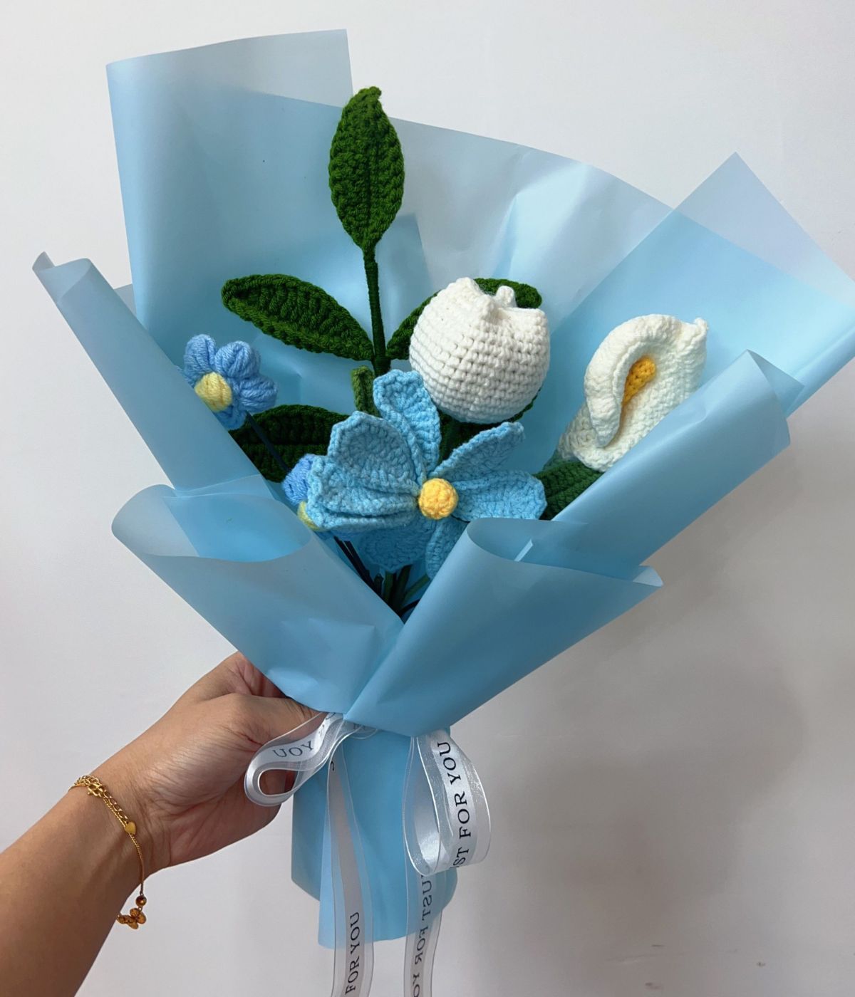 Handgehäkelter Wollblumenstrauß groß in Blau in der Hand einer Frau